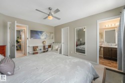 Bedroom featuring ensuite bath, a textured ceiling, ceiling fan, a closet, and light colored carpet - 