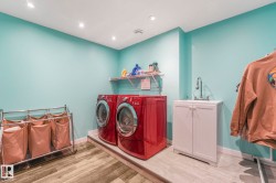 Laundry area with light wood-style flooring, washer and clothes dryer, and recessed lighting - 