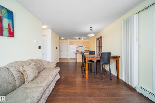 Living room with a baseboard heating unit and dark wood finished floors - 211 4310 33 Street, Stony Plain, AB - Indoor Photo Showing Living Room