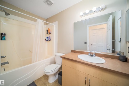 Full bathroom with vanity, shower / bath combination with curtain, and light tile patterned floors - 211 4310 33 Street, Stony Plain, AB - Indoor Photo Showing Bathroom