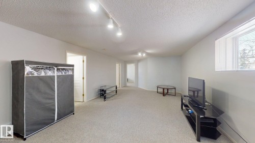 Unfurnished room with rail lighting, a textured ceiling, and light carpet - 17010 84 Street, Edmonton, AB - Indoor