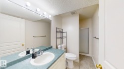 Bathroom with vanity, a shower stall, a textured ceiling, and light tile patterned flooring - 