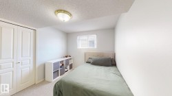 Bedroom featuring a textured ceiling, a closet, and light colored carpet - 