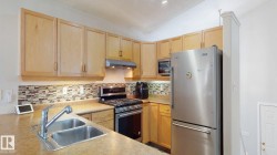 Kitchen featuring light wood finish cabinetry, stainless steel appliances, light countertops, decorative backsplash, and vaulted ceiling - 