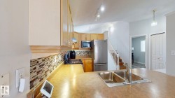 Kitchen featuring decorative backsplash, stainless steel appliances, lofted ceiling, light countertops, and hanging light fixtures - 