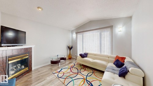 Living room featuring light wood-style flooring and a tile fireplace - 17010 84 Street, Edmonton, AB - Indoor Photo Showing Living Room With Fireplace