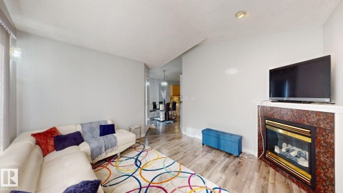 Living room with wood finished floors, a fireplace, and a textured ceiling - 17010 84 Street, Edmonton, AB - Indoor Photo Showing Living Room With Fireplace