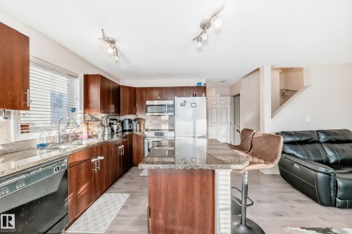 Kitchen featuring appliances with stainless steel finishes, dark stone countertops, a kitchen bar, and a kitchen island - 1285 Cunningham Drive, Edmonton, AB - Indoor Photo Showing Kitchen With Double Sink
