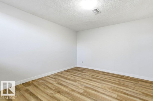 Spare room featuring wood finished floors and a textured ceiling - 10704 96 St Nw, Edmonton, AB - Indoor Photo Showing Other Room
