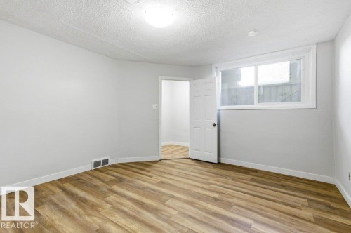 Unfurnished room featuring light wood-style flooring and a textured ceiling - 10704 96 St Nw, Edmonton, AB - Indoor Photo Showing Other Room