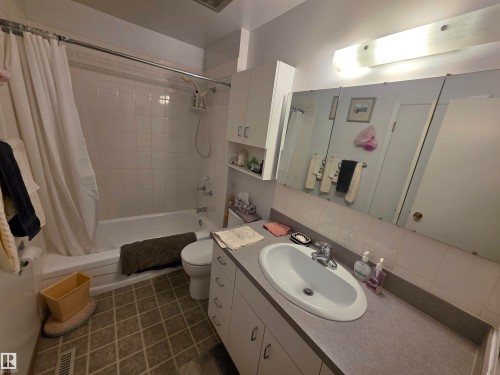 Full bathroom with vanity, shower / bathtub combination with curtain, and dark tile patterned flooring - 4400 45 Avenue, Stony Plain, AB - Indoor Photo Showing Bathroom