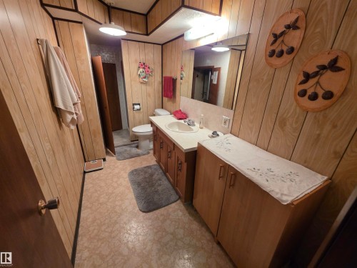 Full bathroom with vanity, wood walls, a shower stall, and light floors - 4400 45 Avenue, Stony Plain, AB - Indoor Photo Showing Bathroom