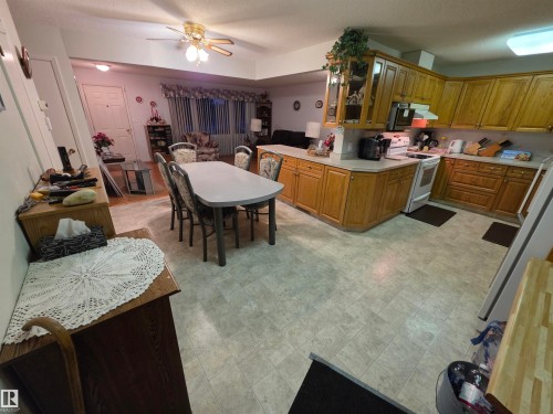 Kitchen with light countertops, freestanding refrigerator, white electric range, and a ceiling fan - 4400 45 Avenue, Stony Plain, AB - Indoor