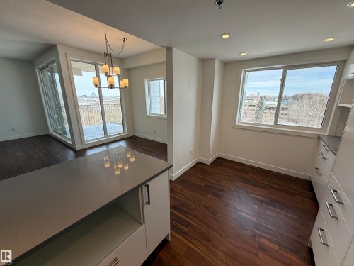 Unfurnished dining area with dark wood-style floors and hanging lights - 605 8728 Gateway Boulevard, Edmonton, AB - Indoor Photo Showing Other Room