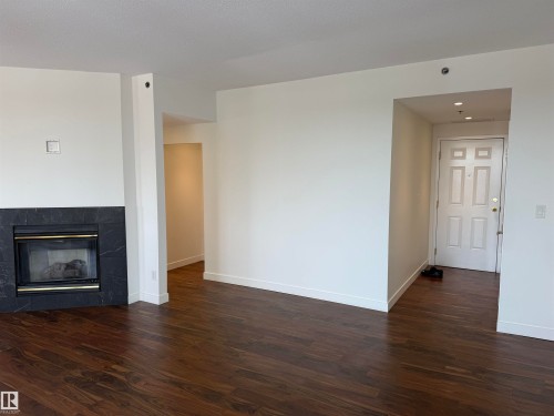 Unfurnished living room with a high end fireplace, dark wood finished floors, and recessed lighting - 605 8728 Gateway Boulevard, Edmonton, AB - Indoor Photo Showing Living Room With Fireplace
