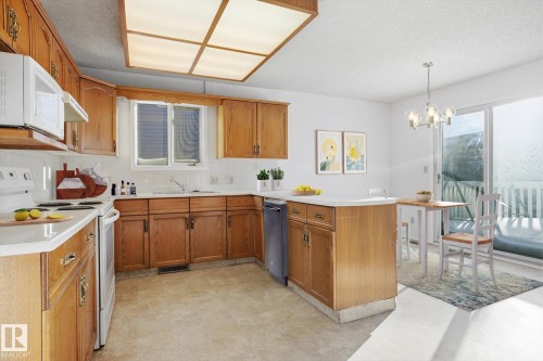 Kitchen featuring white appliances, wood finish cabinets, a peninsula, light countertops, and a textured ceiling - 17816 94 Street, Edmonton, AB - Indoor Photo Showing Kitchen