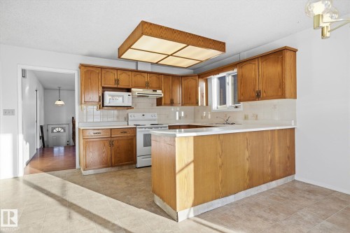 Kitchen featuring light countertops, white appliances, a peninsula, and decorative backsplash - 17816 94 Street, Edmonton, AB - Indoor Photo Showing Kitchen