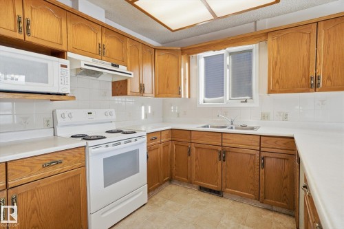 Kitchen with white appliances, wood finish cabinets, tasteful backsplash, and light countertops - 17816 94 Street, Edmonton, AB - Indoor Photo Showing Kitchen With Double Sink