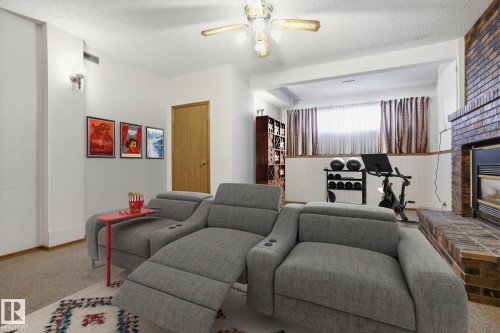 Living area featuring a fireplace, a textured ceiling, ceiling fan, and carpet floors - 17816 94 Street, Edmonton, AB - Indoor Photo Showing Living Room With Fireplace