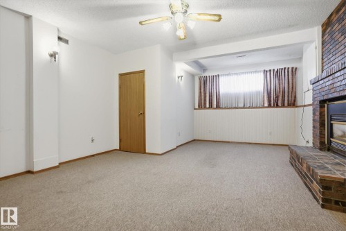Unfurnished living room featuring a textured ceiling, ceiling fan, a fireplace, and light carpet - 17816 94 Street, Edmonton, AB - Indoor Photo Showing Other Room With Fireplace
