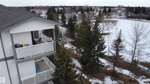 View of snowy exterior featuring a balcony, a residential view, and a shingled roof - 227 16807 100 Avenue, Edmonton, AB - Outdoor