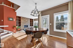 Dining space with built in features, light wood-style flooring, hanging lights, a textured ceiling, and a stone fireplace - 