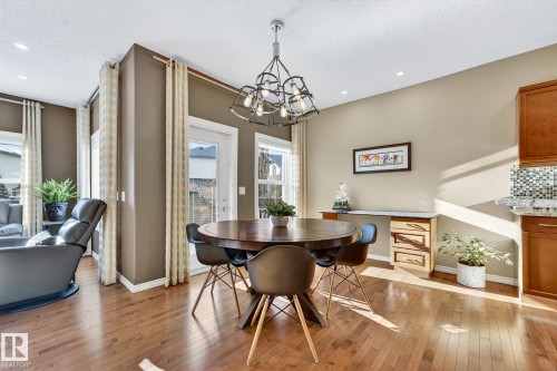 Dining area with light wood finished floors, a chandelier, and a textured ceiling - 2036 Hilliard Place, Edmonton, AB - Indoor Photo Showing Dining Room