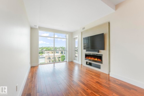 Higher ceilings on the 8th floor means you have a taller window bathing the living room with sunlight in the afternoon.  Professionally installed zebra blinds are included. - 814 200 Bellerose Drive, St. Albert, AB - Indoor Photo Showing Living Room With Fireplace