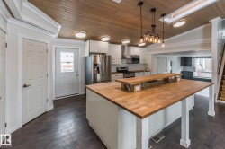 Kitchen with a skylight, white cabinets, a vaulted wooden ceiling, a center island with sink, and a kitchen bar - 