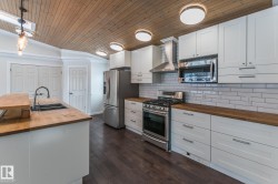 Kitchen featuring wooden counters, stainless steel appliances, white cabinetry, a vaulted wooden ceiling, and ornamental molding - 