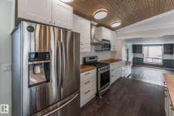 Kitchen with stainless steel appliances, open floor plan, butcher block counters, white cabinets, and tasteful backsplash - 