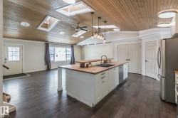 Kitchen with butcher block countertops, ornamental molding, stainless steel appliances, a vaulted wooden ceiling, and hanging light fixtures - 