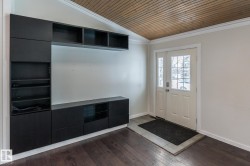 Entrance foyer with a vaulted wooden ceiling, ornamental molding, and dark wood-style flooring - 