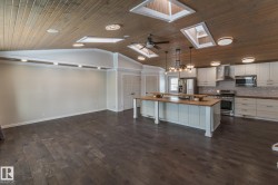 Kitchen with butcher block counters, a kitchen island, a kitchen bar, white cabinets, and decorative light fixtures - 