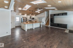 Kitchen with butcher block counters, open floor plan, white cabinets, pendant lighting, and a center island - 