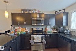 Kitchen featuring stainless steel appliances, dark stone countertops, pendant lighting, and backsplash - 