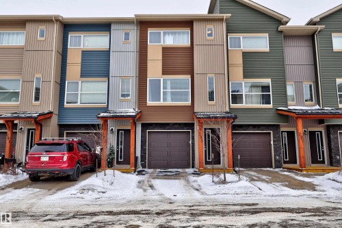 Kitchen with stainless steel appliances, a peninsula, dark wood finish cabinets, decorative light fixtures, and a textured ceiling - 295 401 Southfork Drive, Leduc, AB - Indoor Photo Showing Kitchen With Upgraded Kitchen