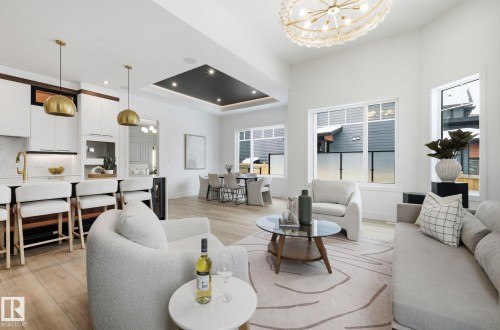 Living room with suspended lighting, a tray ceiling, light wood-type flooring, and healthy amount of natural light - 296 165 Avenue, Edmonton, AB - Indoor Photo Showing Living Room