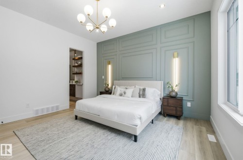 Bedroom with an accent wall, light wood finished floors, suspended lighting, and a decorative wall - 296 165 Avenue, Edmonton, AB - Indoor Photo Showing Bedroom