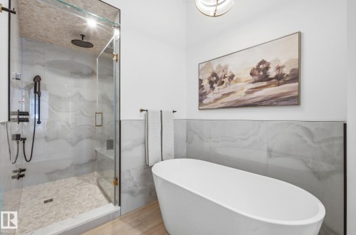 Bathroom with a soaking tub, a marble finish shower, tile walls, wood finished floors, and a wainscoted wall - 296 165 Avenue, Edmonton, AB - Indoor Photo Showing Bathroom