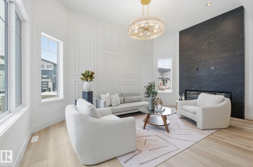 Living area featuring wood finished floors, an accent wall, hanging lights, a premium fireplace, and a decorative wall - 296 165 Avenue, Edmonton, AB - Indoor Photo Showing Living Room