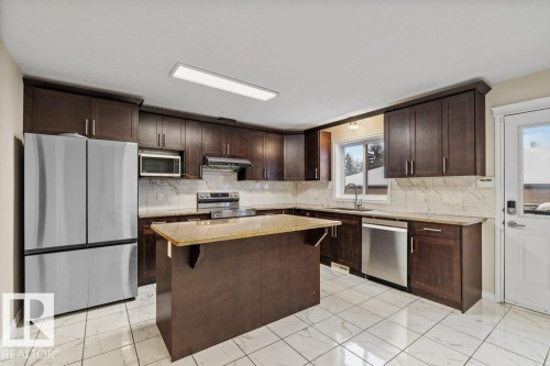 Kitchen with dark brown cabinetry, appliances with stainless steel finishes, and light marble finish flooring - 10639 70 Avenue, Edmonton, AB - Indoor Photo Showing Kitchen With Upgraded Kitchen