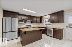Kitchen with dark brown cabinetry, appliances with stainless steel finishes, and light marble finish flooring - 