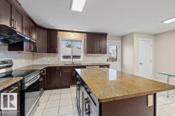 Kitchen featuring dark brown cabinets, light marble finish floors, stainless steel range with electric stovetop, dark stone countertops, and a textured ceiling - 