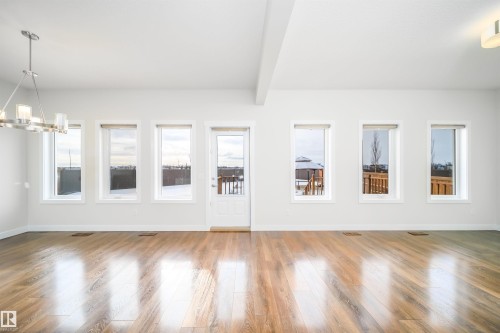 Unfurnished living room featuring wood-type flooring, beam ceiling, and a chandelier - 19743 26 Avenue, Edmonton, AB - Indoor Photo Showing Other Room