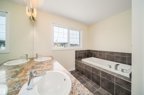 Bathroom featuring a bath, double vanity, and dark tile patterned floors - 19743 26 Avenue, Edmonton, AB - Indoor Photo Showing Bathroom