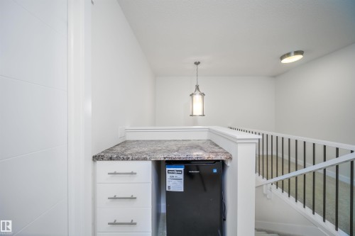 white cabinetry, pendant lighting, black dishwasher, and light stone counters - 19743 26 Avenue, Edmonton, AB - Indoor Photo Showing Other Room