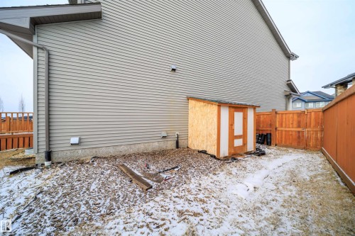 View of snowy exterior with a fenced backyard and a storage unit - 19743 26 Avenue, Edmonton, AB - Outdoor With Exterior