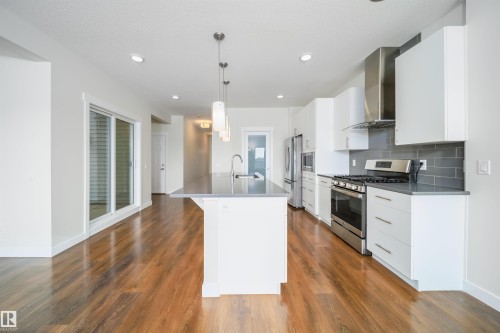Kitchen featuring white cabinets, stainless steel appliances, decorative light fixtures, and a center island with sink - 19743 26 Avenue, Edmonton, AB - Indoor Photo Showing Kitchen With Upgraded Kitchen
