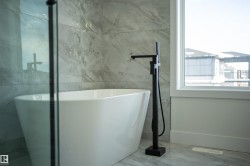 Bathroom featuring a freestanding tub and marble finish floors - 
